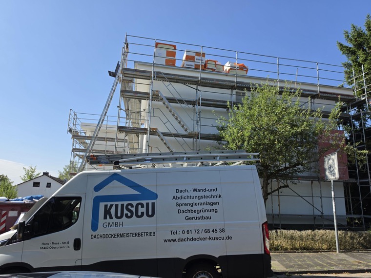 Kuscu-Firmenwagen vor einer eingerüsteten Liegenschaft in Kelkheim — energetische Flachdachsanierung